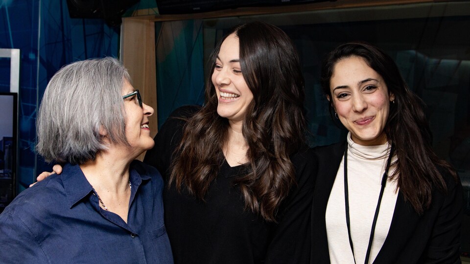 Trois femmes sourient et échangent des regards complices dans un studio de radio.