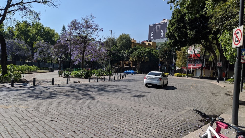 Une place urbaine désertée avec une seule voiture sur la route.