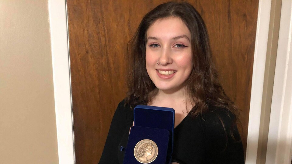 Une jeune femme montre sa médaille académique du Gouverneur Général du Canada