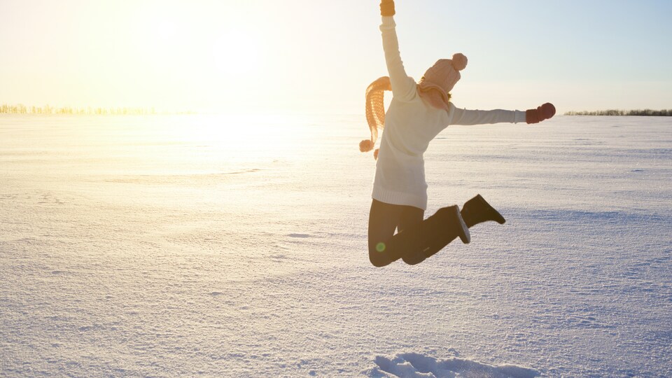 Une femme qui saute dans la neige.
