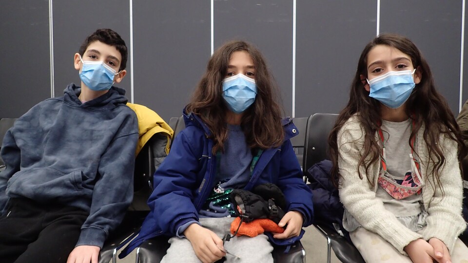 Les trois enfants assis, regardent le photographe.