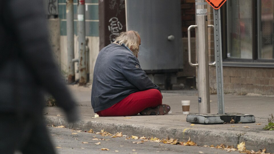 Un mendiant assis sur un trottoir.