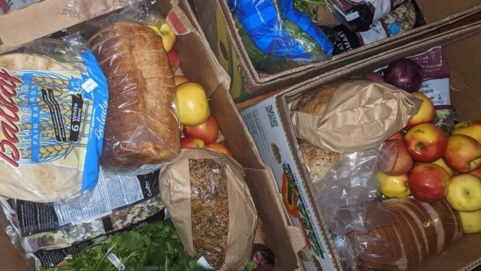 Du pain, des fruits et des légumes disposés dans des paniers en carton.