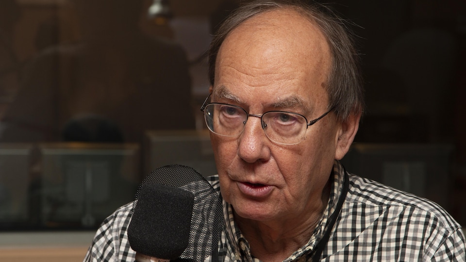 Michel Fortmann devant un micro radio dans les studios de Radio-Canada.