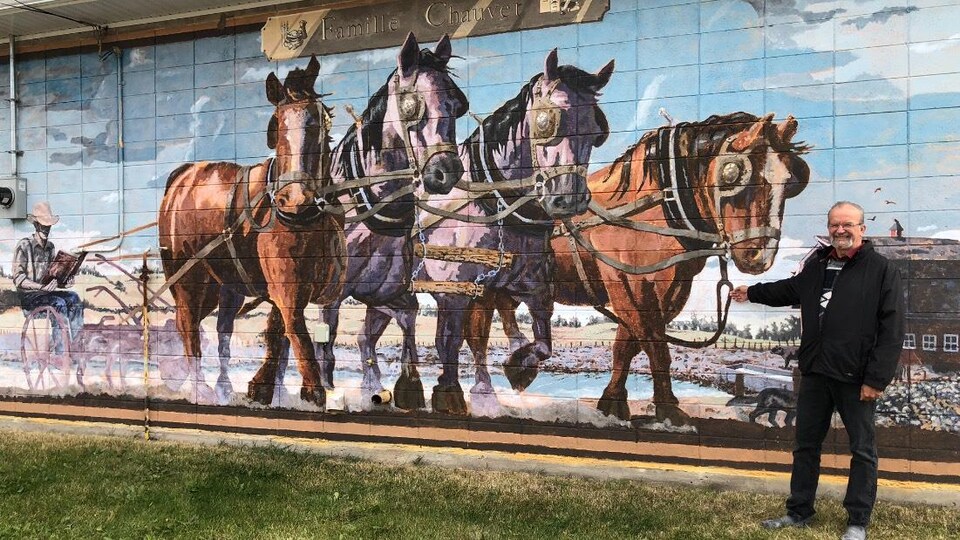 Peinture murale de Legal représentant un jeune homme lisant sur une charrue tirée par des chevaux.