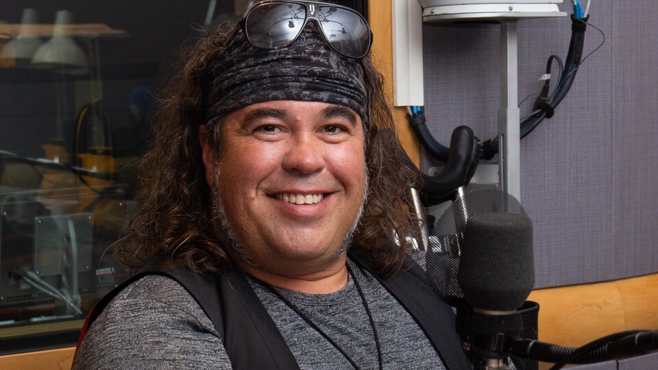 Le chanteur au bandeau sourit en studio.