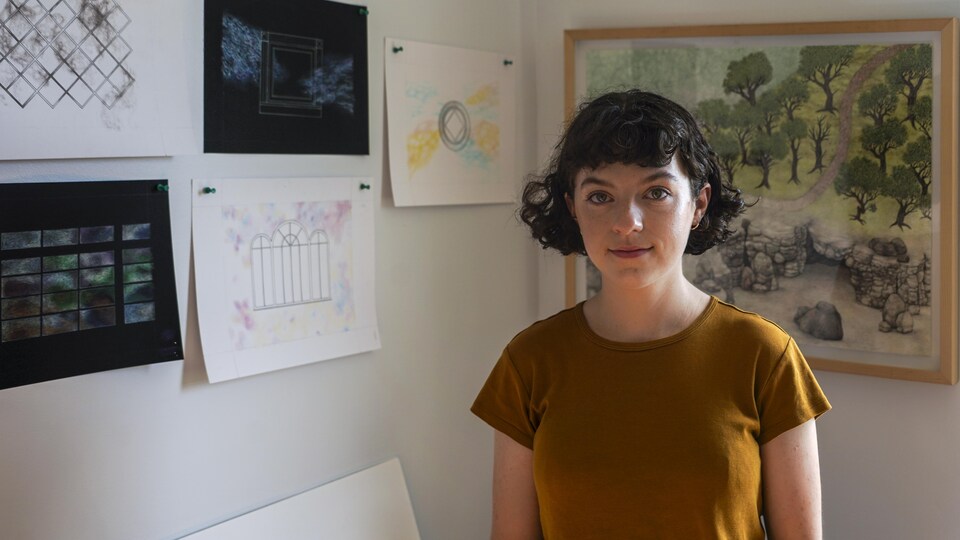 Lisa Theriault devant des tableaux accrochés au mur.
