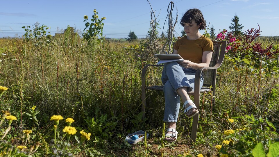 Lisa Theriault assise, en train de dessiner dans un jardin.