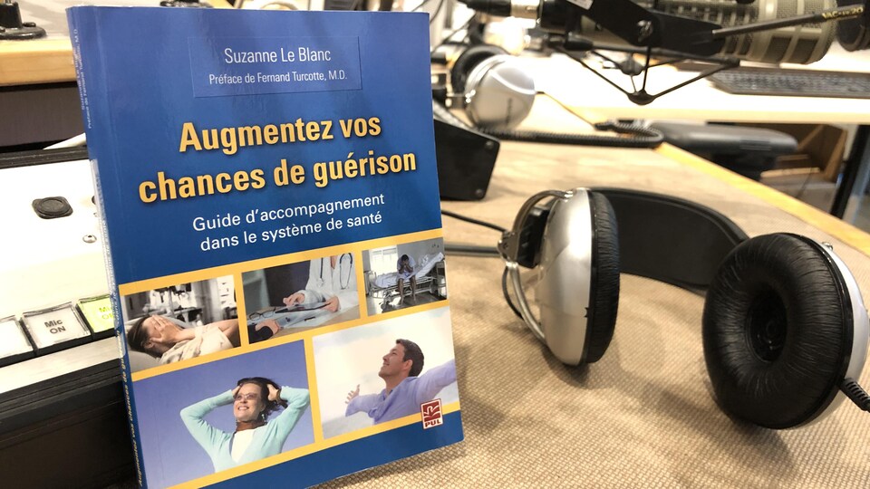 Le livre est appuyé près d'une paire d'écouteurs et d'un micro.