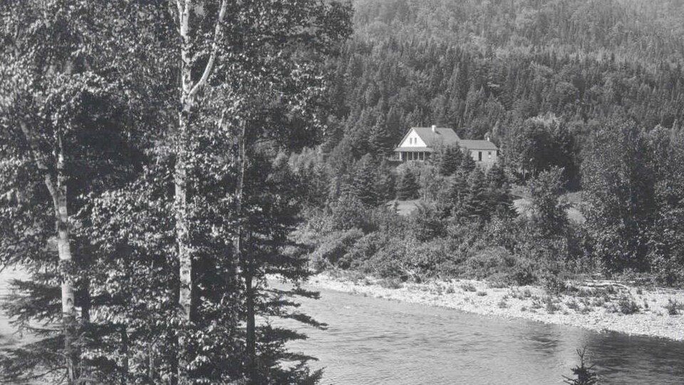 Photo en noir et blanc de 1910 où l'on voit le camp de pêche, photographié à partir de l'autre rive de la rivière Cascapédia