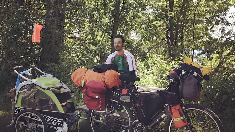 Un homme avec son chien et sa bicyclette chargée de bagages.