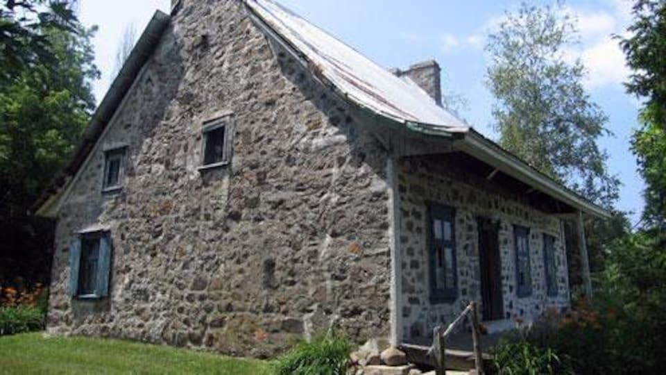 Une maison ancestrale en pierres avec du gazon vert. 