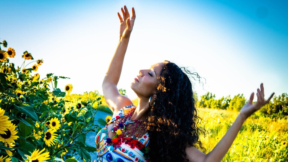 Une femme danse au soleil près d'un chant de tournesols.