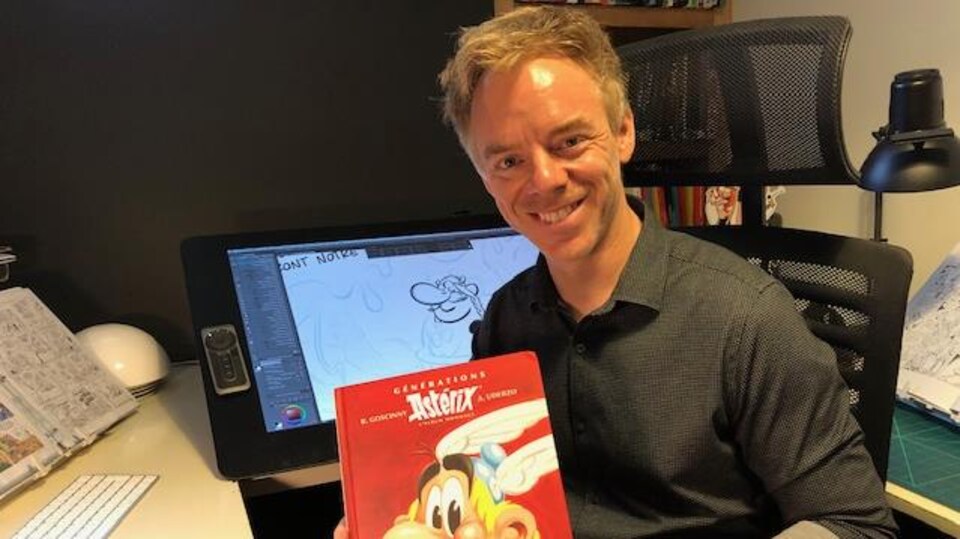 Un homme souriant tient un livre dans ses mains.