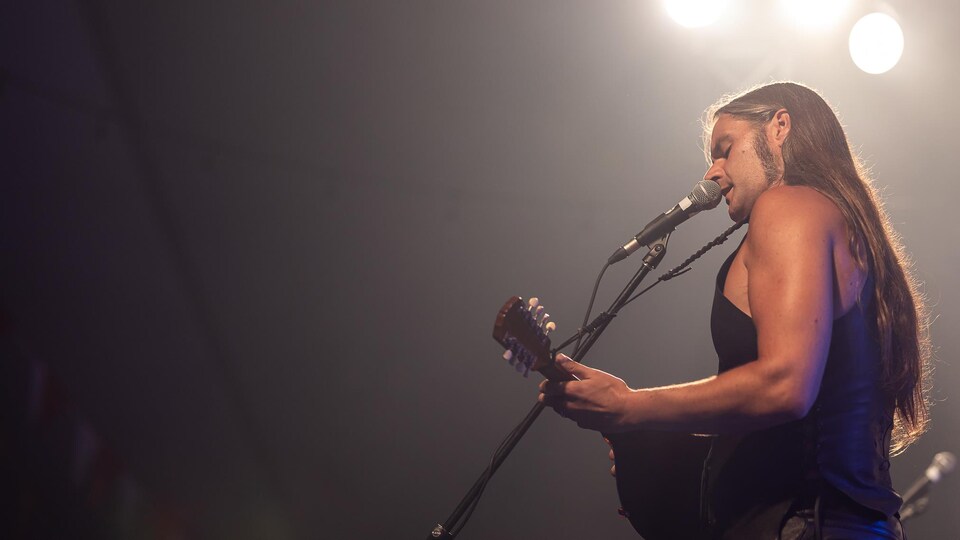 Le chanteur devant un micro, sous les projecteurs.