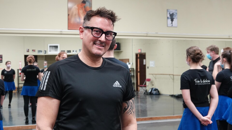 Un danseur sourit à la caméra dans un studio de danse. 