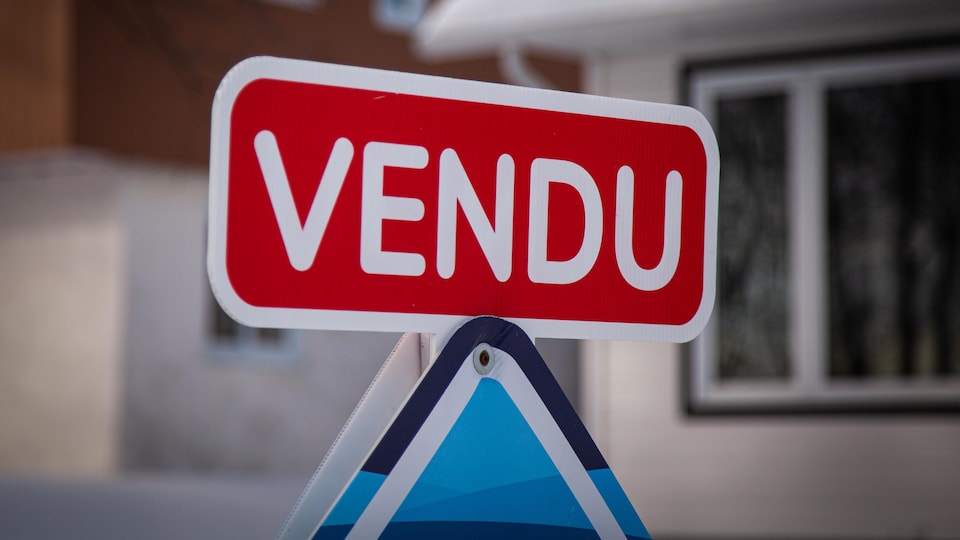 Carton « vendu » installé sur une affiche de courtier immobilier