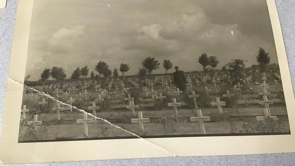 Une personne debout au milieu de dizaines de croix dans un cimetière militaire canadien en Europe.