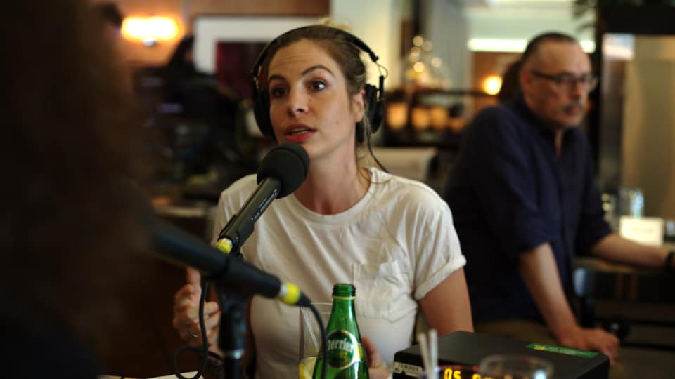Marie-Lyne Joncas, derrière un micro, parle à Christiane Charette, de dos.