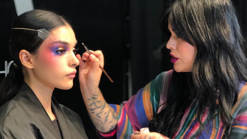 L'artiste maquilleuse Marika D'Auteuil fait des retouches au maquillage d'une mannequin.