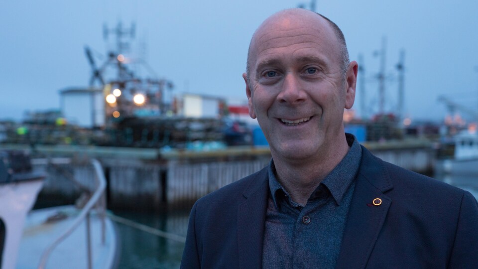 Mario Cyr, photographe sous-marin, sourit devant un port.