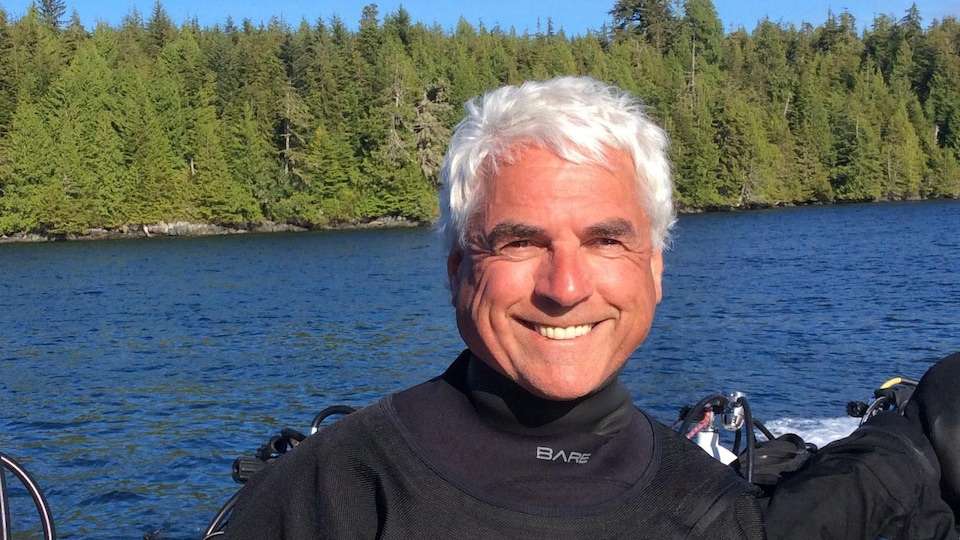 Mario Longpré souriant  en habit de plongée sous-marine sur un bateau .