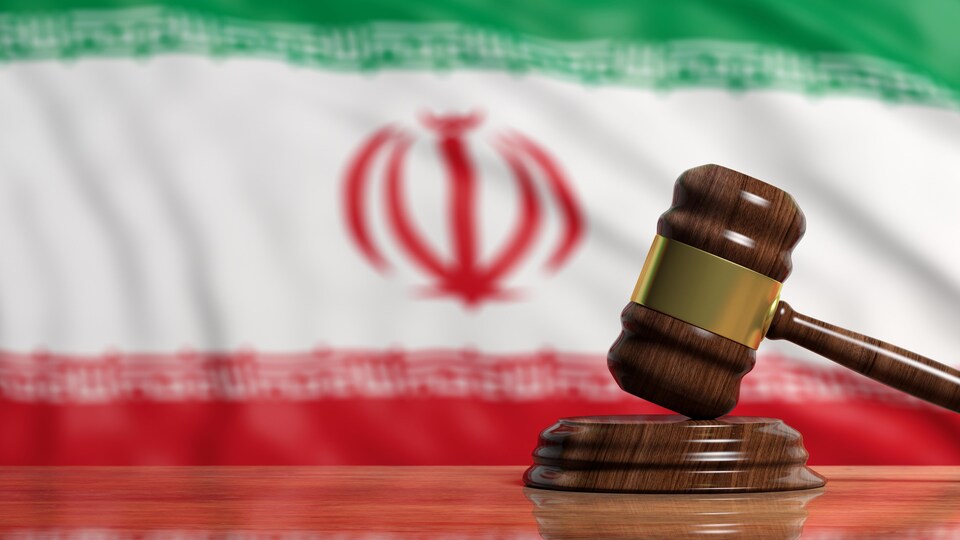 Un marteau de président est montré devant un drapeau de l'Iran.