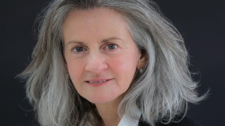 Une femme sourit sur fond noir.
