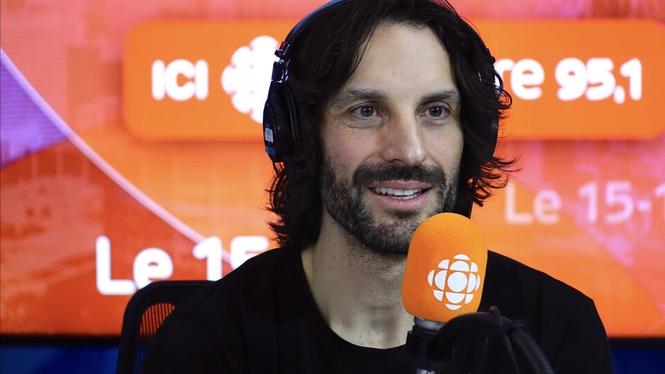 Mathieu Cyr derrière un micro dans un studio radio de Radio-Canada.