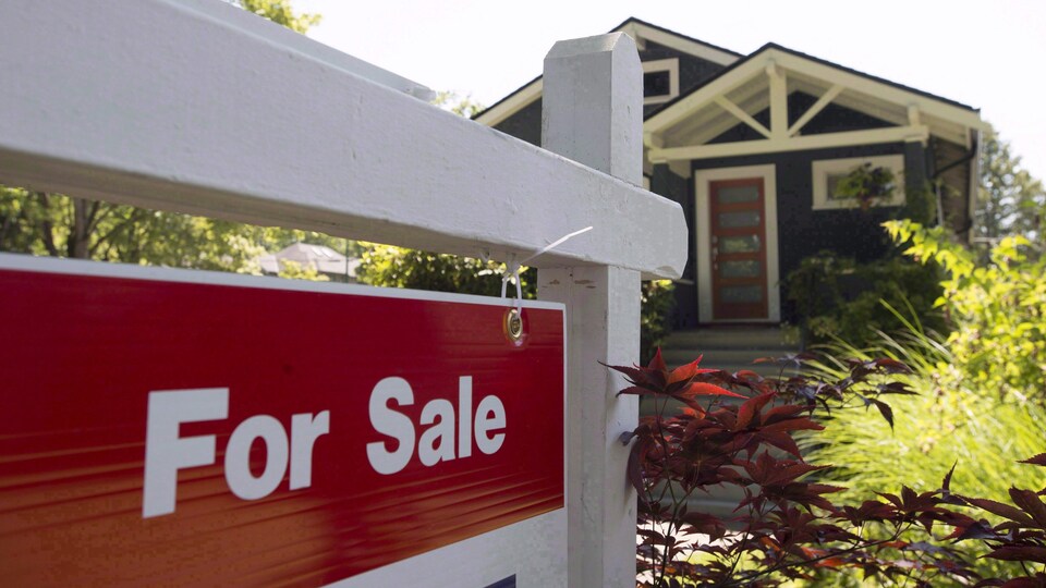 Une enseigne qui dit « For Sale » devant un bungalow de Vancouver.