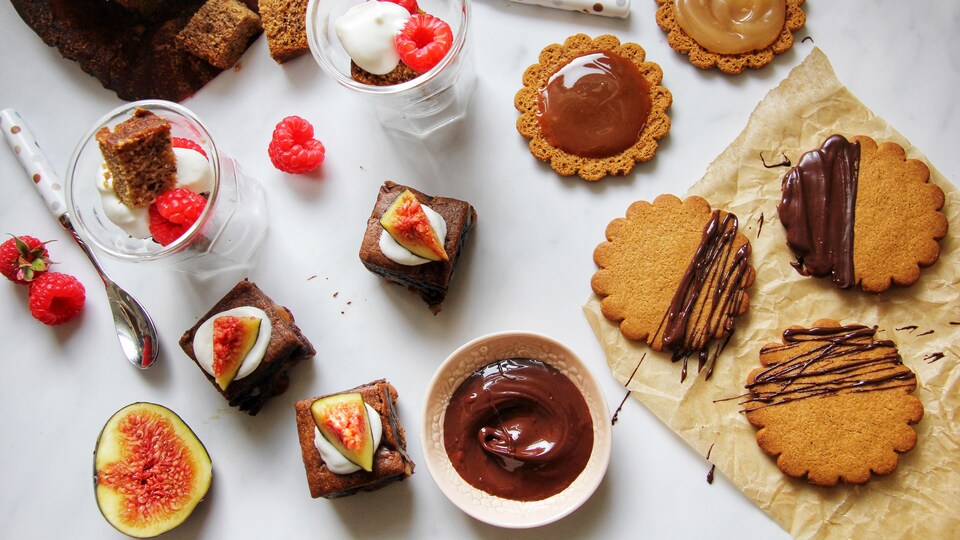 Des verrines avec du pain aux bananes, des brownies au chocolat style petits fours et des biscuits décorés avec du chocolat et du caramel.