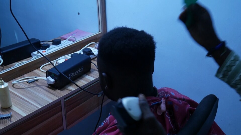 Un jeune homme est assit devant un mirroir, on peut voir un accumulateur de Reeddi sur la commode devant lui.