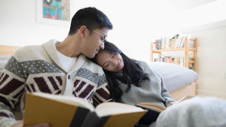 Deux amoureux lisent des livres et boivent du café dans leur chambre.