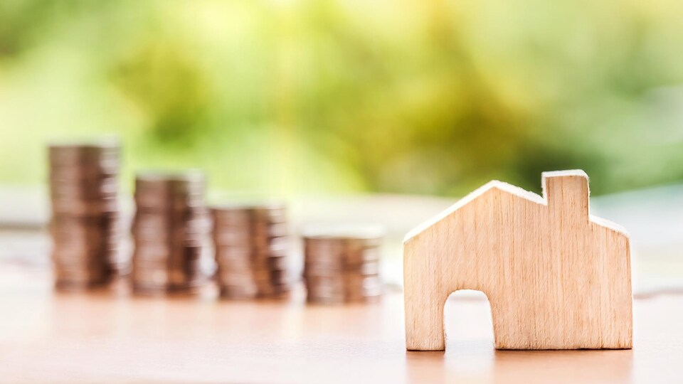 Une maison en bois devant une rangée de pièces de monnaie.