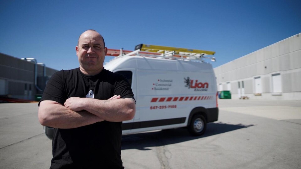 Hubert Larouche se tient debout les bras croisés devant son camion.