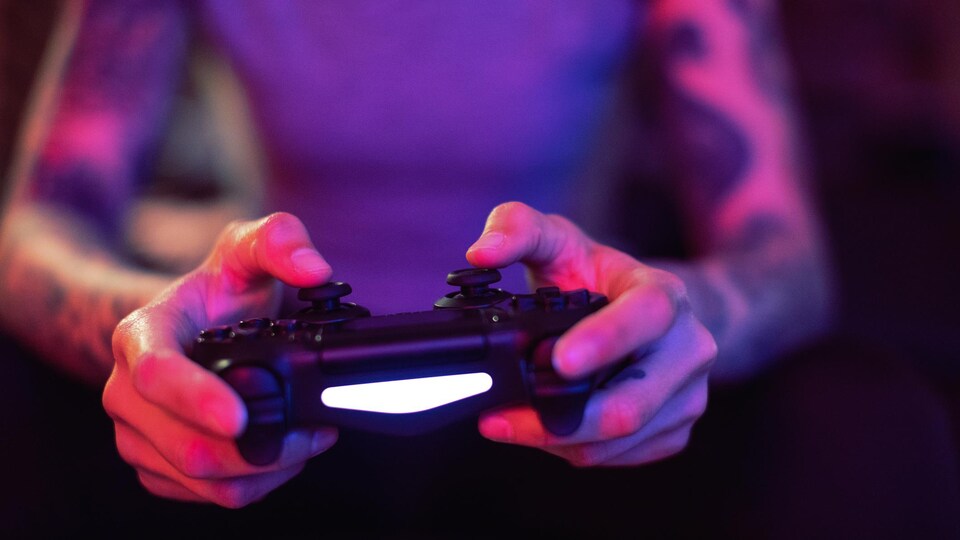 Une personne est assise sur un sofa et joue à un jeu vidéo.