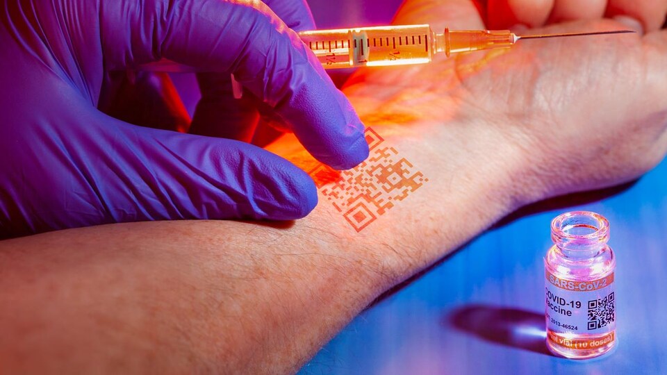 Une main portant un gant, un avant-bras avec un code QR et une seringue avec le vaccin contre la COVID-19.