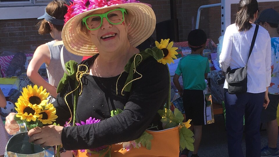 Sylvie Lacombe porte un costume orné de tournesols et un chapeau de paille.
