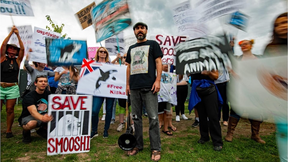 Phil Demers (au centre), entouré de manifestants qui brandissent des affiches dénonçant le traitement des animaux de Marineland.