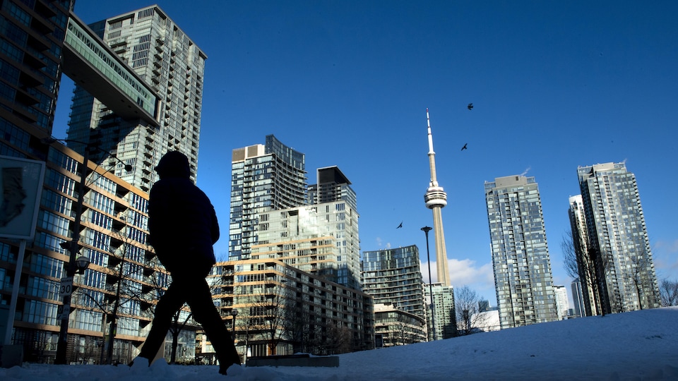 Un passant en hiver dans un quartier de tours à condos à Toronto.