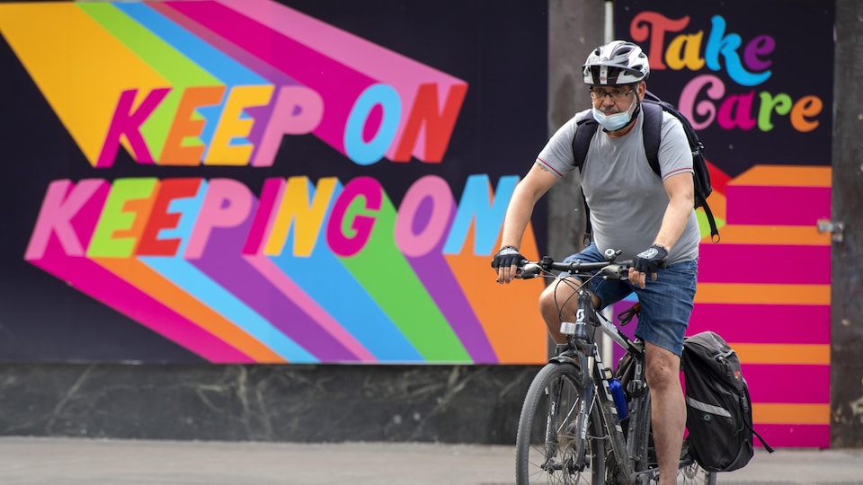 Un homme à vélo devant une murale colorée au centre-ville de Toronto.