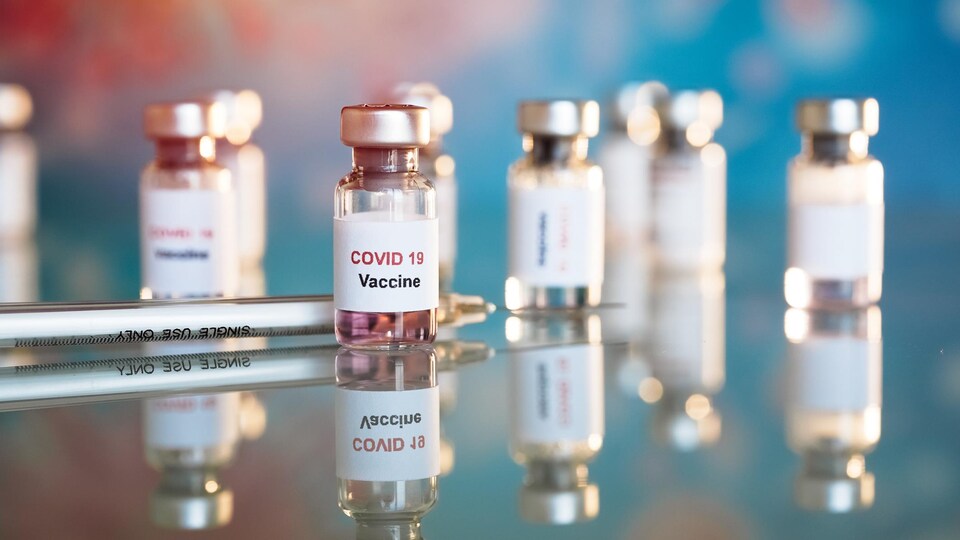 Des fioles de vaccin contre la COVID-19 alignées sur une table.