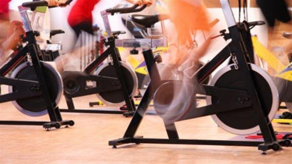 Des jambes qui pédalent sur des vélos stationnaires. 