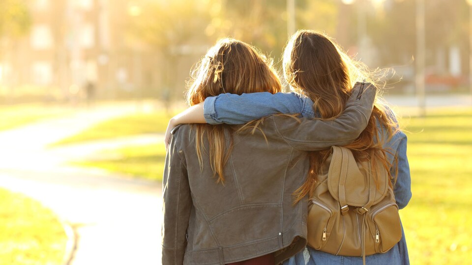 Deux femmes se tiennent très proche dans un parc.