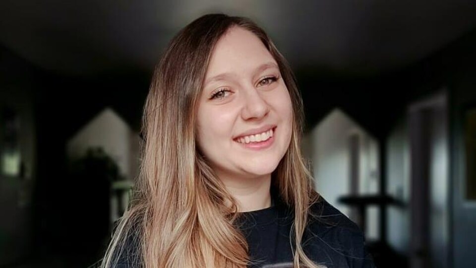 Une jeune femme avec les cheveux longs souriant à la caméra.