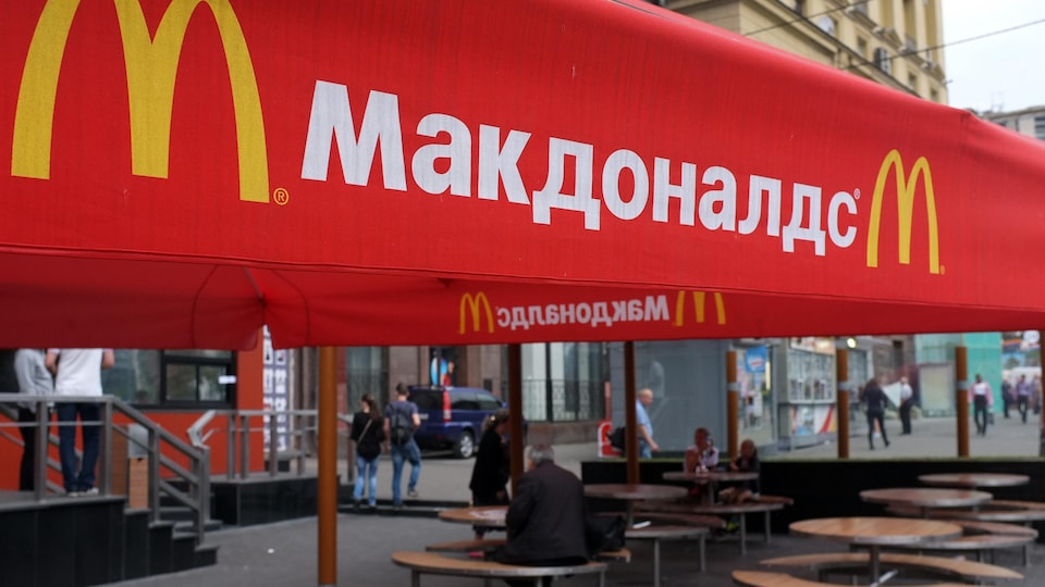 Des gens sont assis à des tables sur la terrasse du premier restaurant McDonald's a avoir ouvert ses portes en Union soviétique en 1990, à Moscou le 21 août 2014.