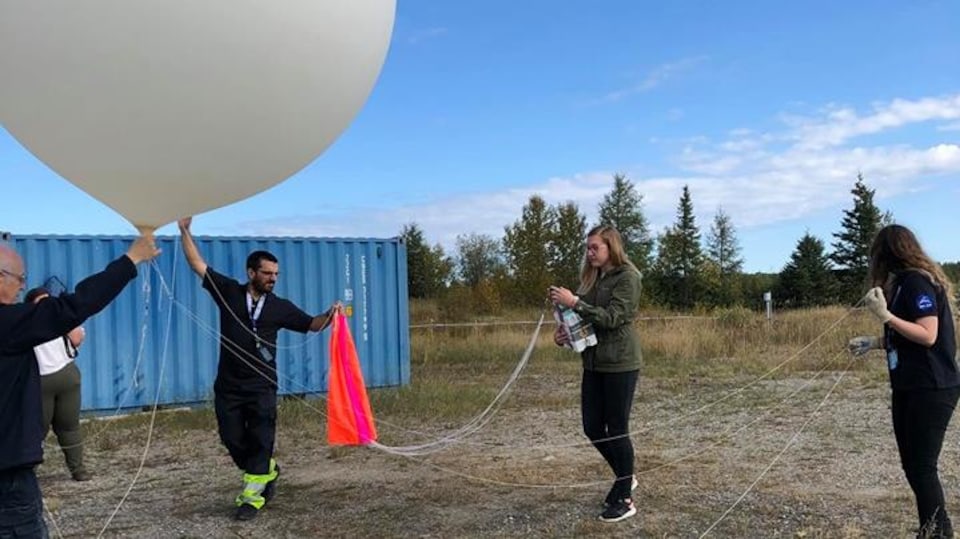 Quatre personnes manipulent un ballon stratosphérique