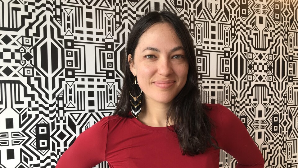 Caroline Monnet devant une murale composée de nombreux motifs.