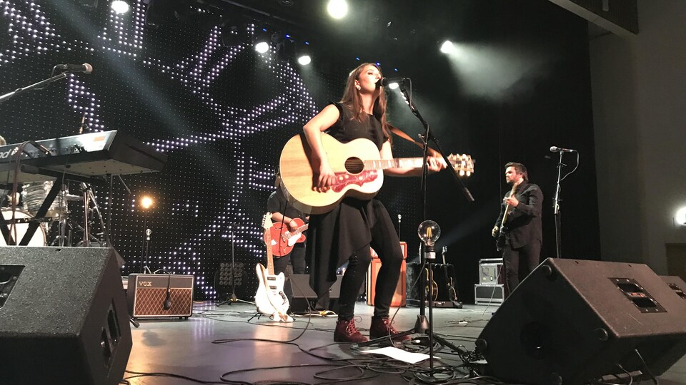 Une chanteuse sur scène avec une guitare.