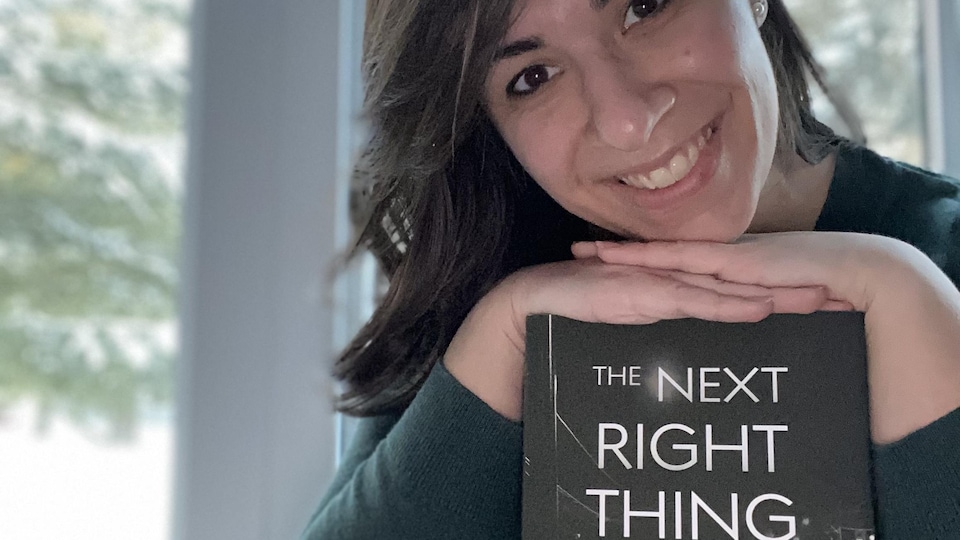 Une femme souriante présente un livre